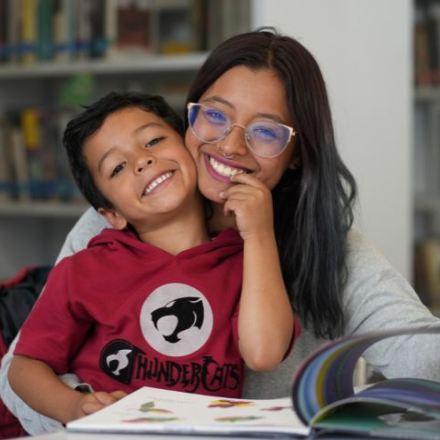 Madre e hijo posando sonrientes en una biblioteca