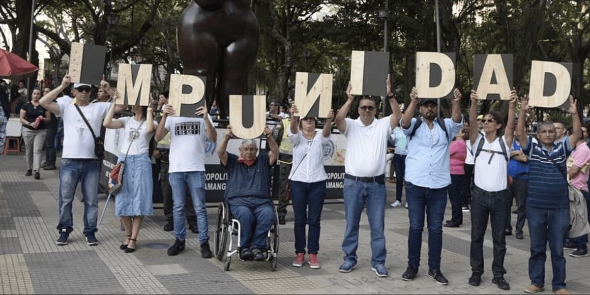 Personas con una cartel con la palabra impunidad.