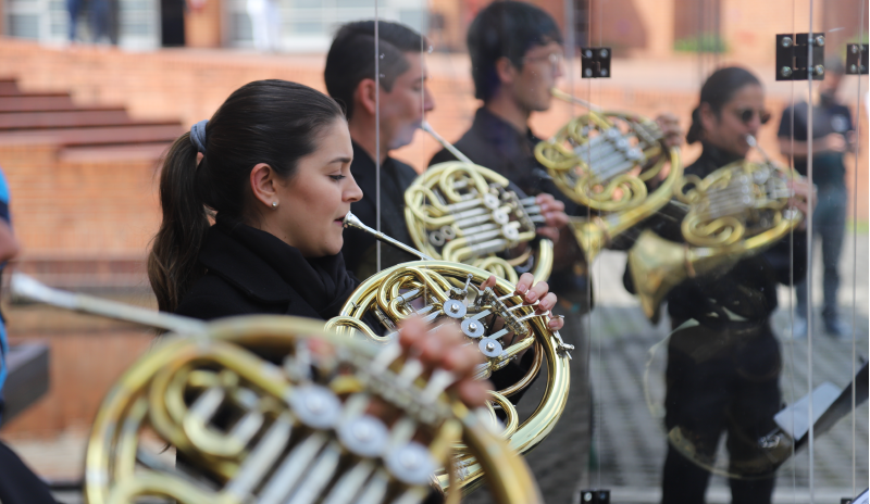 Músicos juveniles interpretando una tuba con traje negro. Se logran ver en la imagen tres hombre y una mujer