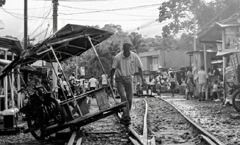 Foto en blanco y negro de ferrocarril y una persona caminando