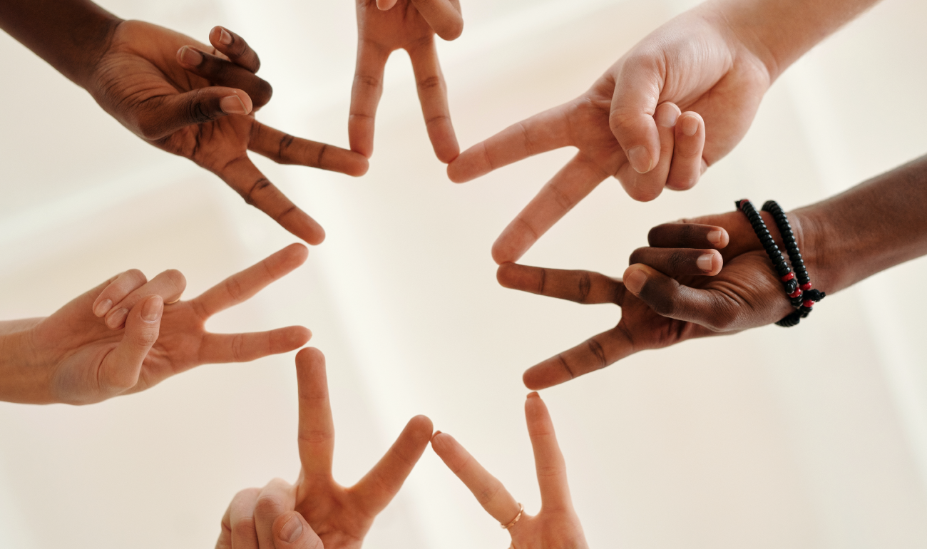 Manos de seis jóvenes que a través del símbolo de paz y amor forman una estrella de seis puntas