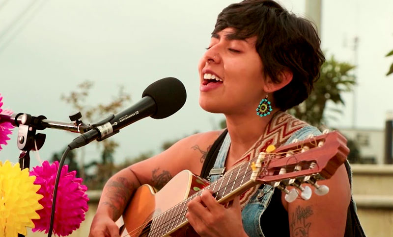 mujer cantando y tocando una guitarra