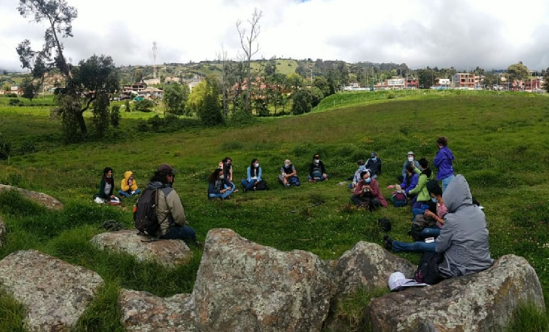 Personas sentadas en una zona verde al aire libre en círculo