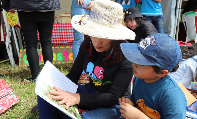 Mujer y niño leyendo un libro al aire libre