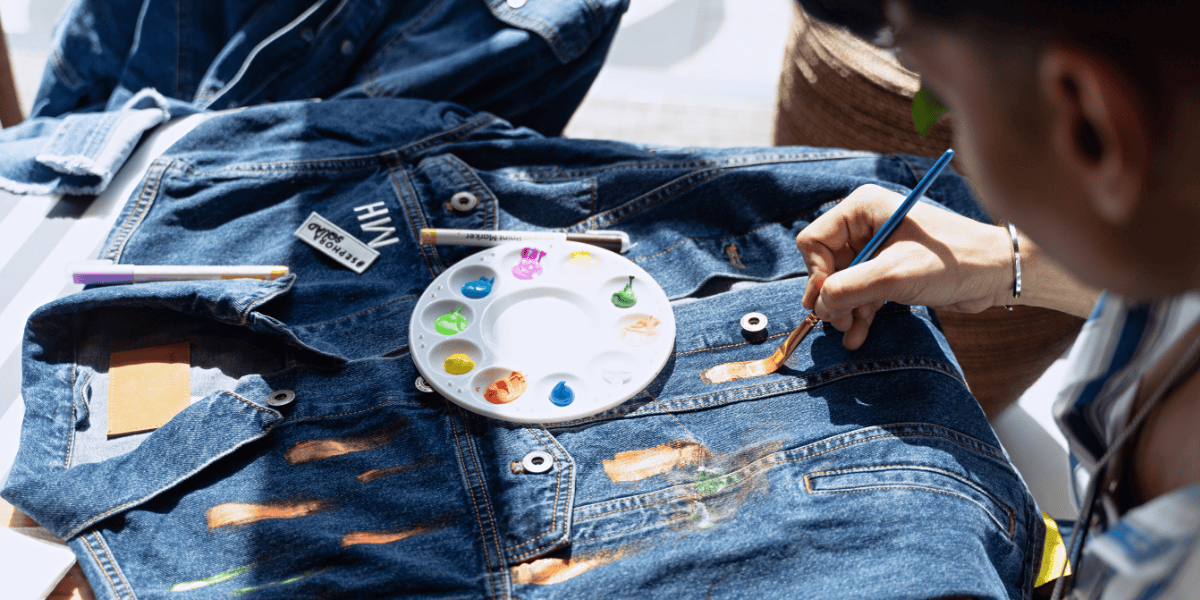 Persona pintando una chaqueta de denim con pinturas