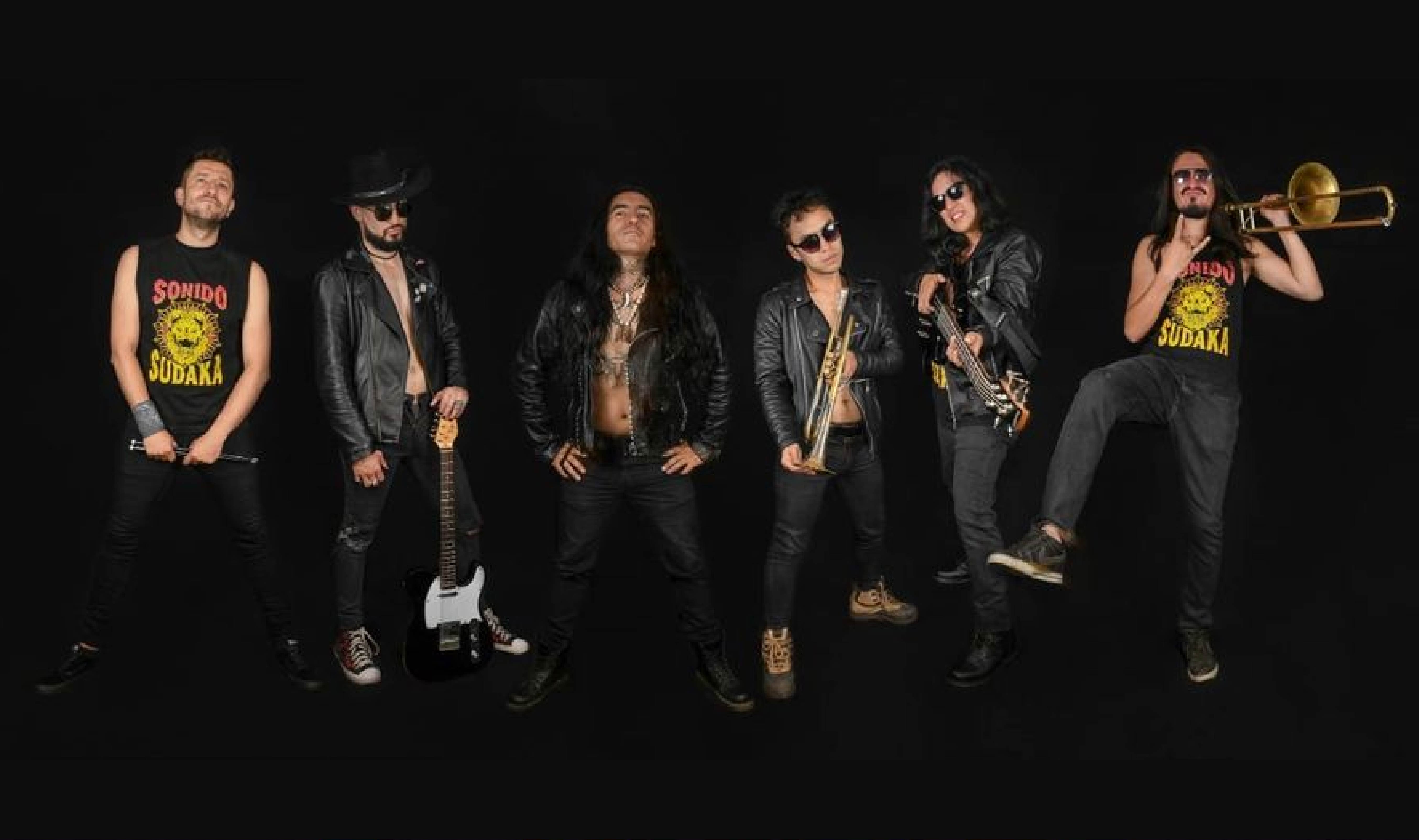 Foto de la agrupación. Se ven seis músicos con trajes de cuero o ropa completamente negra con el instrumento que interpretan o parte de éste en la manos.