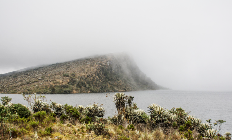 Imagen de un lago y una montaña cubierta de nubes 