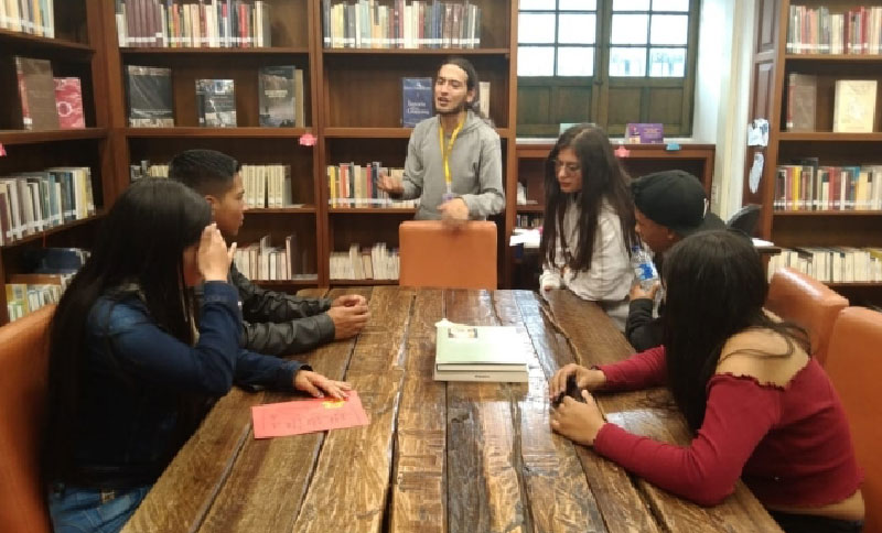Jóvenes escuchando a un instructor en una biblioteca