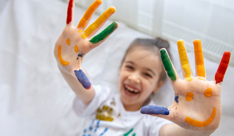 Niña con manos pintadas de colores