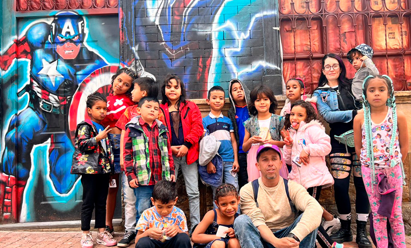 grupo de niñas y niños frente a un grafiti