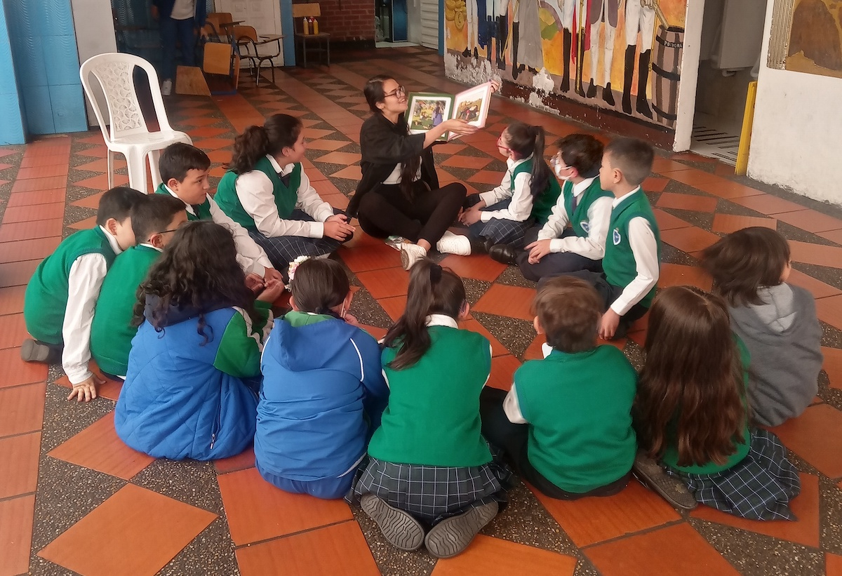 Profesora mostrando un libro a un grupo de niños