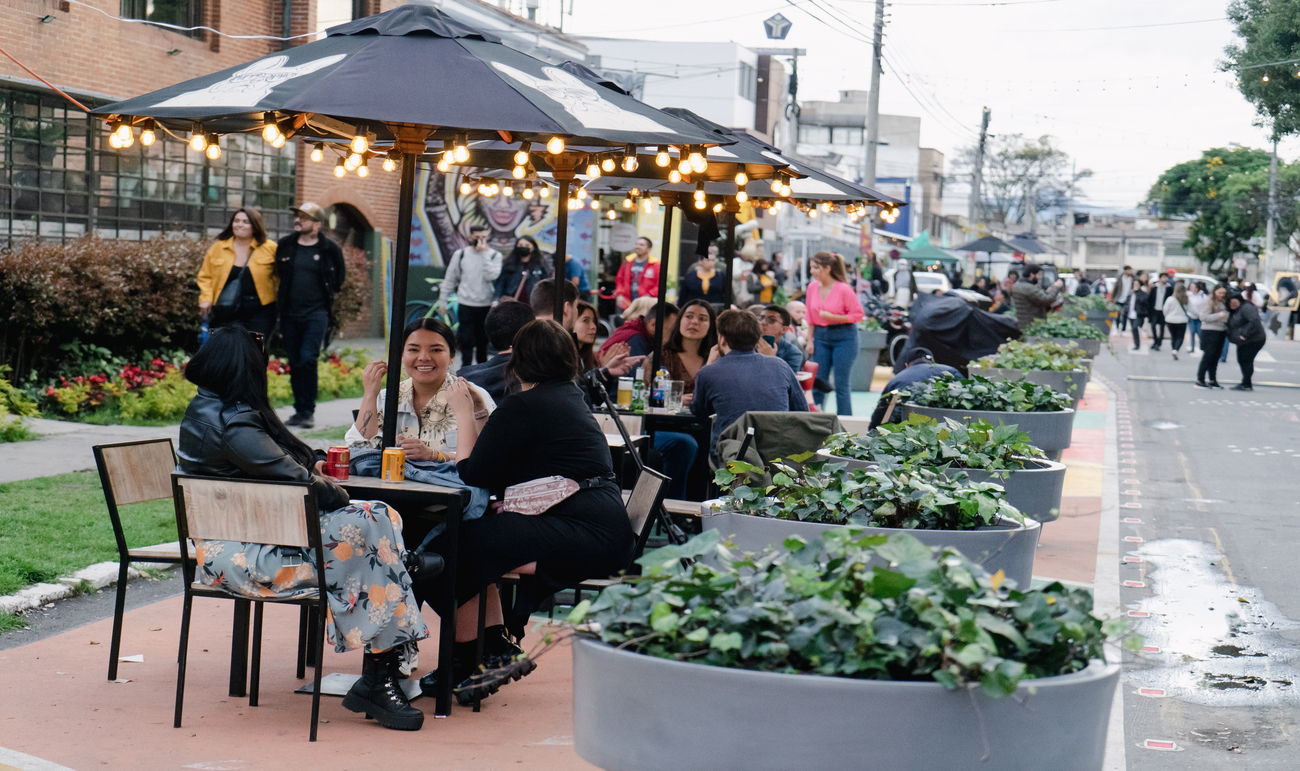 Personas reunidas en mesas en la calle