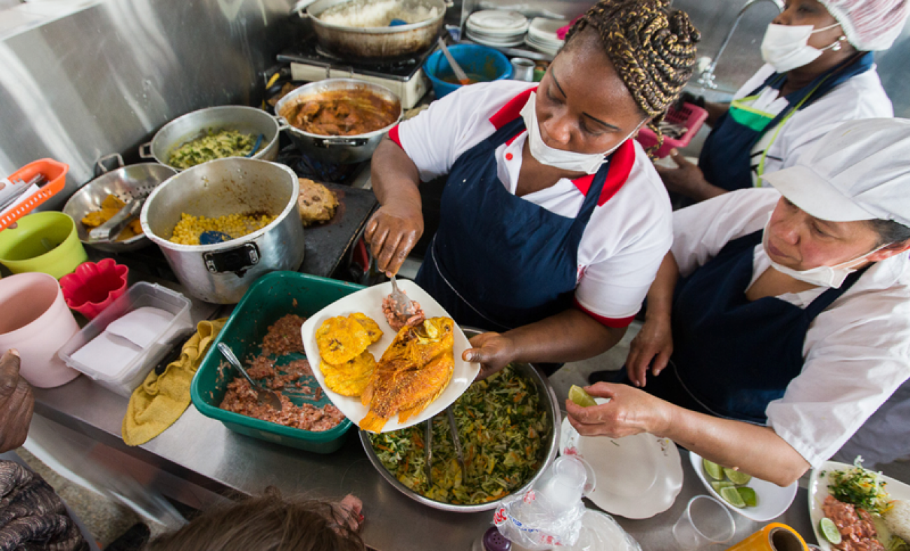 Mujer en una cocina sirviendo un plato de comida