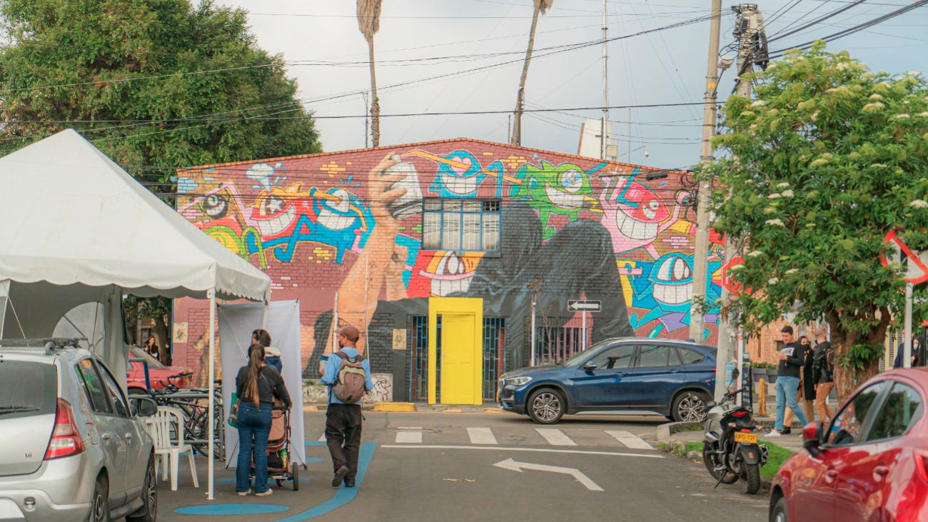 Calle con casa , carpa, personas y carros