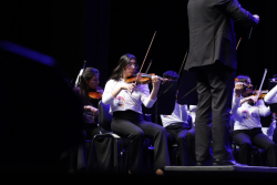 Niño de orquesta sinfónica ejecuta violín