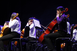 Niños de orquesta sinfónica ejecutan violonchelo