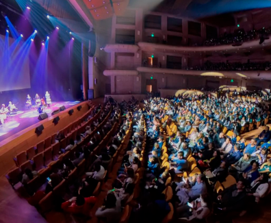 Multitud de personas en un teatro observando una presentación artística