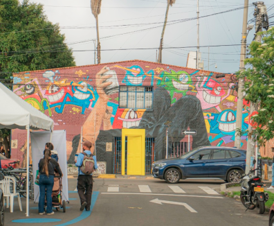 Calle con casa , carpa, personas y carros