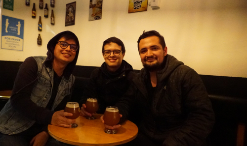 Tres jóvenes reunidos disfrutando de una cerveza.