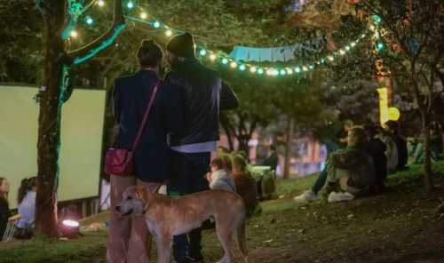 Dos personas y un perro en un evento de noche en los Distritos Creativos