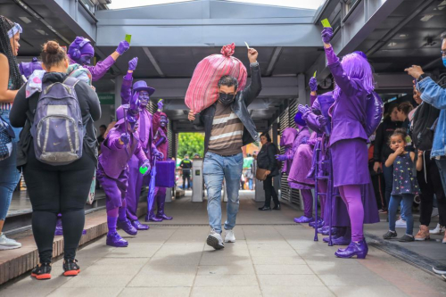 Personas vestidas de violeta saludando a ciudadano
