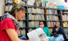 mujer leyendo un lebro a varias personas